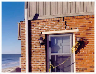 A brick wall with a stair-step crack running above a door