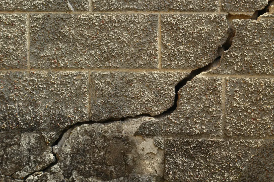 A cracked concrete block foundation wall