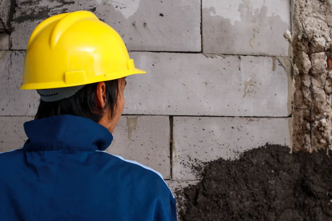 A worker inspecting a foundation wall